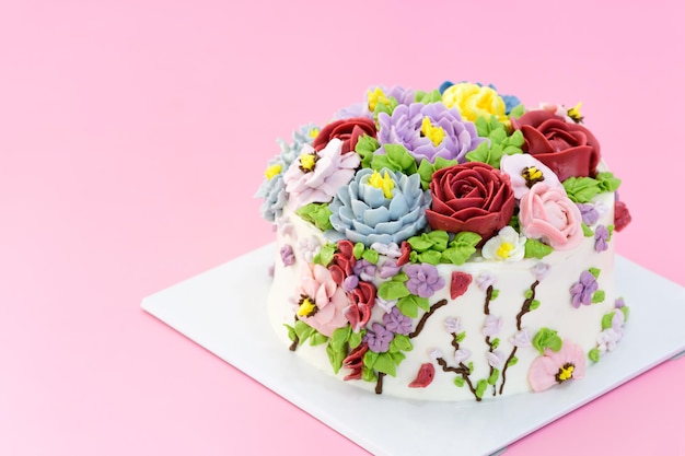 Torta fatta in casa decorata con bellissimi fiori su sfondo rosa, concetto di torta minimale