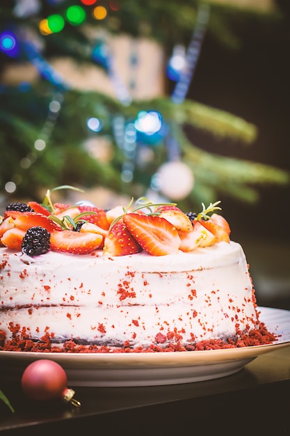 Torta fatta in casa Red Velvet decorata con panna e frutti di bosco su sfondo natalizio