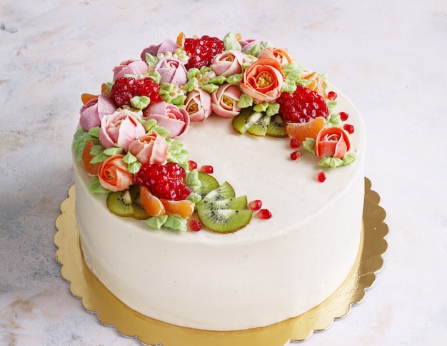 Torta festiva con crema di fiori e frutti su una luce