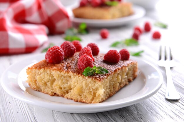 Torta fresca con lampone in zolla bianca sul primo piano della tavola in legno