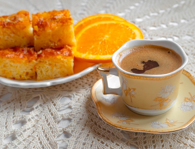 Torta greca all'arancia con fette d'arancia e caffè su una tovaglia lavorata a maglia fatta a mano in Grecia