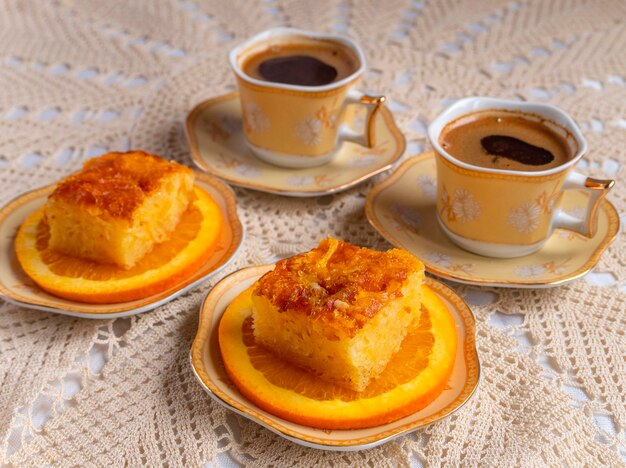 Torta greca all'arancia con fette d'arancia e caffè su una tovaglia lavorata a maglia fatta a mano in Grecia