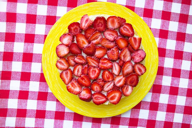 Torta luminosa e deliziosa della fragola su un tovagliolo rosso in una gabbia