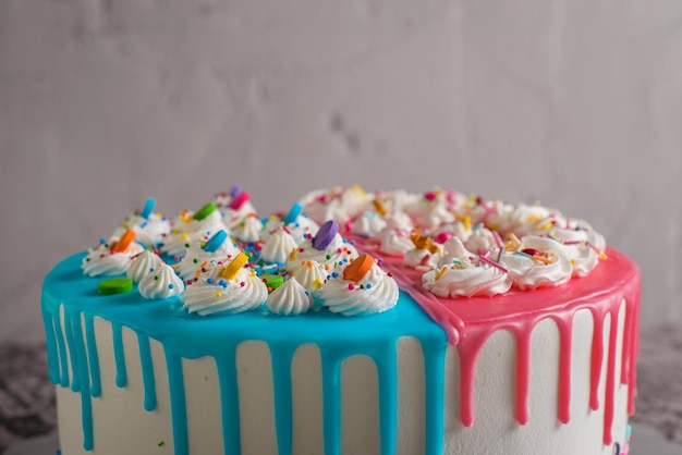 Torta molto colorata decorata con glassa blu e rosa su un tavolo di cemento