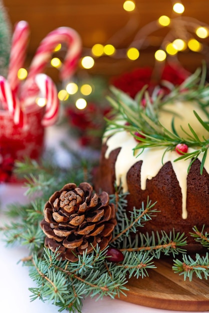 Torta natalizia al caramello, decorata con cioccolato bianco, mirtillo rosso, rosmarino e decorazioni di Capodanno. Prodotti da forno festivi. Messa a fuoco selettiva morbida. Verticale