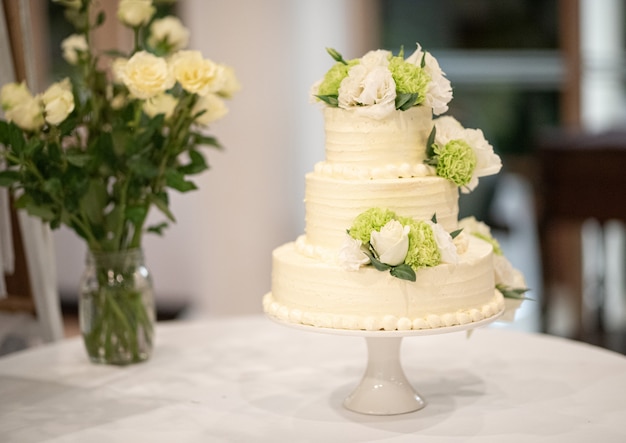 Torta nunziale decorata con i fiori su una tavola