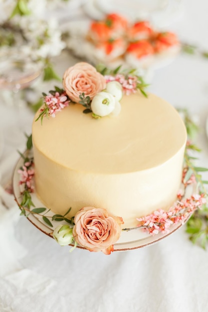 Torta nuziale color crema bianca decorata con fiori e rami in fiore