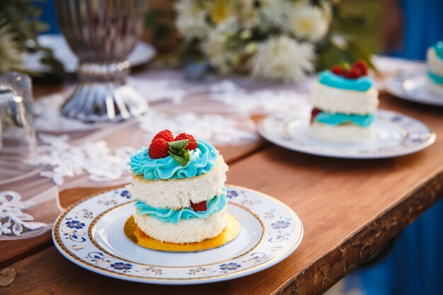 Torta nuziale con lamponi su tavola festiva in legno