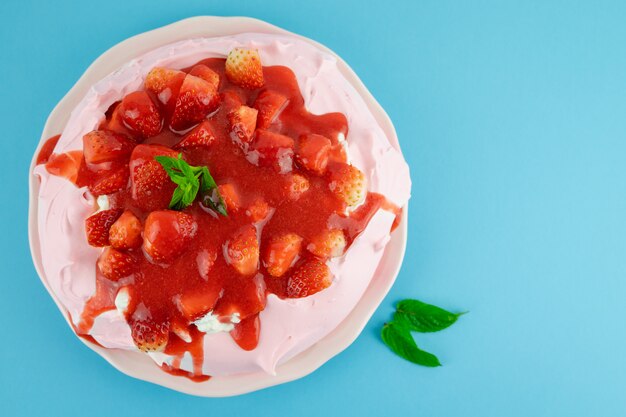 Torta Pavlova con fragole su sfondo blu.