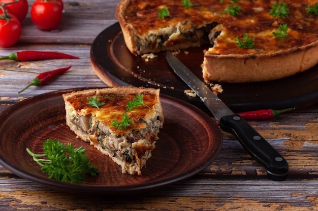 Torta quiche francese tradizionale con pollo e funghi su un tavolo di legno