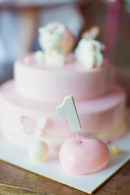 Torta rosa con glassa a specchio e unicorno al cioccolato bianco Torta su un supporto per torta bianco Primo concetto di festa di compleanno