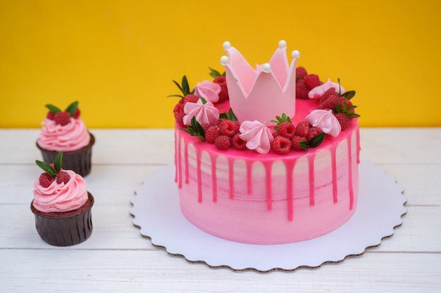 Torta rosa decorata con corona della principessa, bacche di lampone e marshmallow