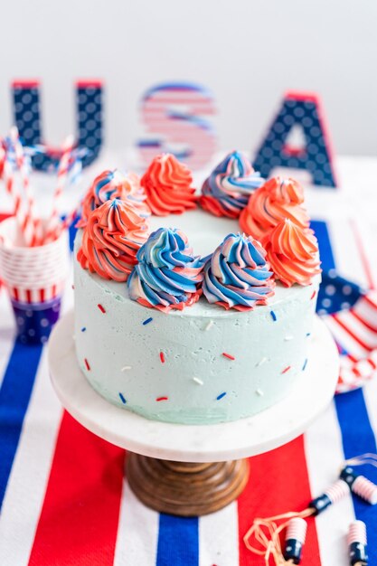 Torta rotonda alla vaniglia rossa, bianca e blu con glassa di crema al burro per la celebrazione del 4 luglio.