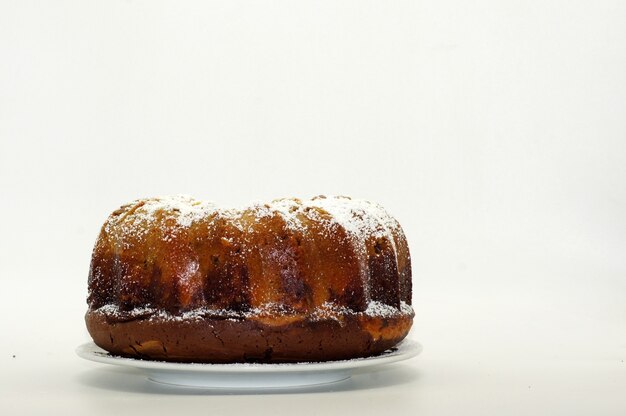 Torta rotonda con zucchero in polvere isolato su una parete bianca