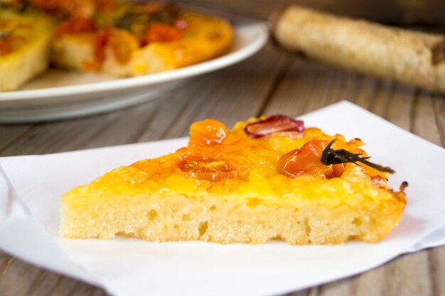 Torta rustica con formaggio e pomodorini su un tavolo di legno.