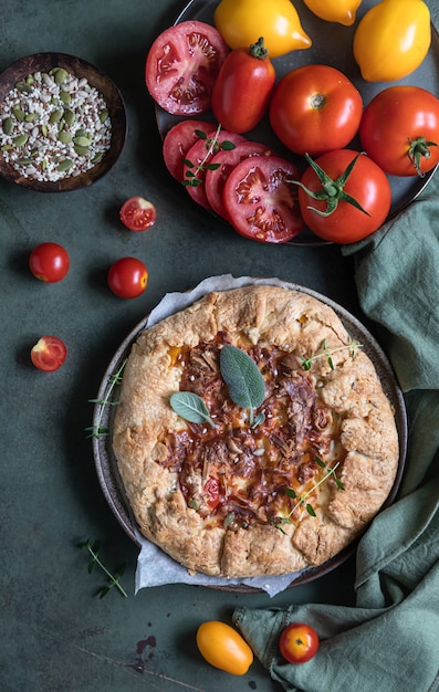 Torta salata al pomodoro open pie o galette con pomodorini e formaggio decorata con erbe aromatiche