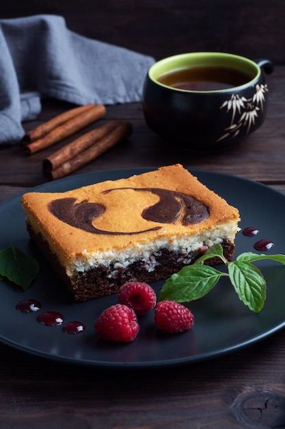 Torta su un piatto di brownie al cioccolato e cheesecake alla ricotta con lamponi