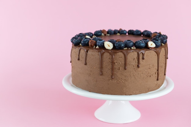 Torta vegana al cioccolato con mirtilli e nocciole su fondo rosa