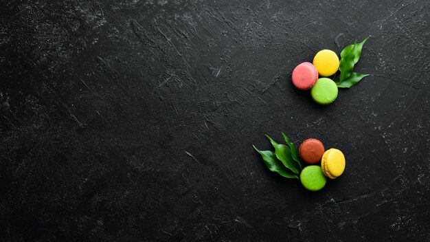 Torte colorate amaretti Su uno sfondo di pietra nera Vista dall'alto Spazio libero per il testo