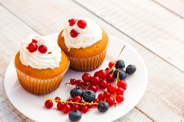 Torte con crema e frutti di bosco su assi di legno