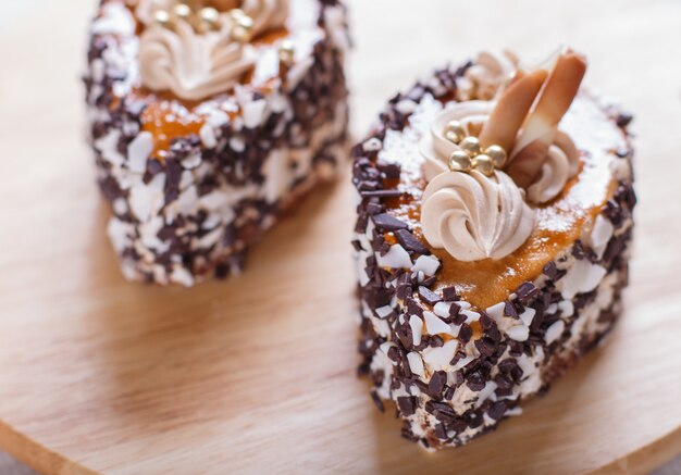 Torte con scaglie di cioccolato e decorazioni di crema sul bordo di legno