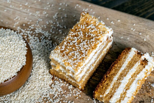 Torte cremose alla crema e caramello cosparse di semi di sesamo durante la preparazione del dolce torta a strati con semi di sesamo