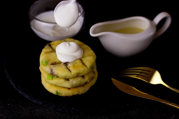 Torte di formaggio su un piatto di ardesia su sfondo nero. Cheesecake con versamento di panna acida