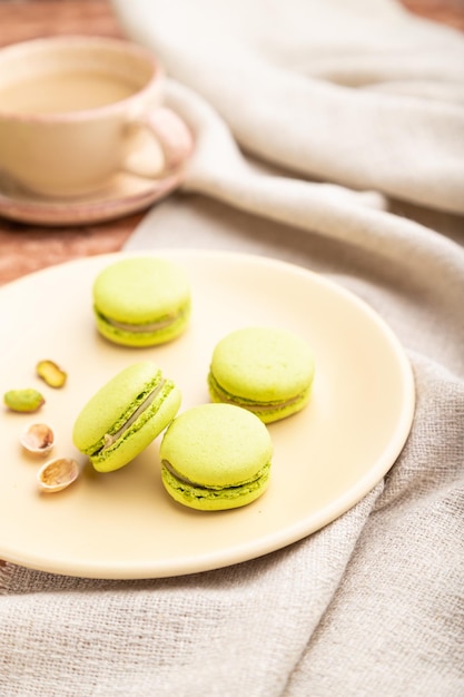 Torte di macarons o amaretti verdi con una tazza di caffè su uno sfondo di cemento marrone Fuoco selettivo vista laterale