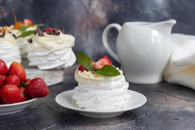 Torte di meringa Pavlova con panna montata e fragole fresche foglie di menta Messa a fuoco selettiva