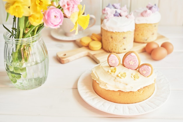 Torte di Pasqua sul tavolo, amaretti, uova e bouquet di fiori in vasaio