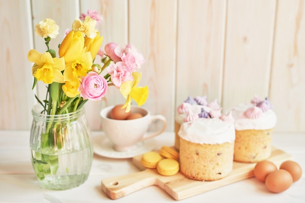 Torte di Pasqua sul tavolo, amaretti, uova e bouquet di fiori in vasaio