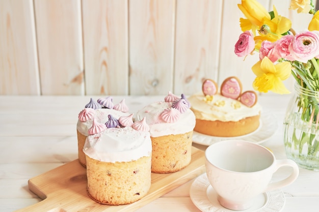 Torte di Pasqua sul tavolo, amaretti, uova e bouquet di fiori in vasaio