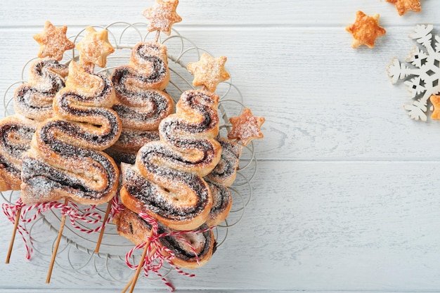 Torte di pasta sfoglia a forma di albero di Natale con ripieno di cioccolato zucchero in polvere e lecca-lecca su fondo di legno bianco vecchio Antipasto di Natale Capodanno Idea festiva per la cena di Natale o Capodanno