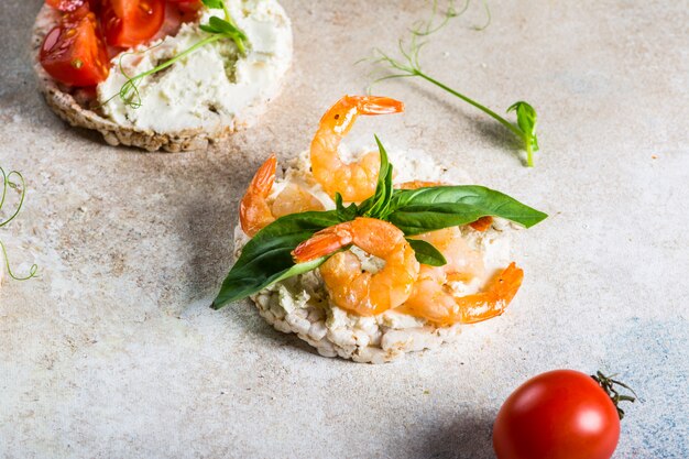 Torte di riso soffiato con gamberi e avocado a bordo. Merenda ai frutti di mare. Pane croccante, croste di pane. concetto di dieta alimentare. Basilico. Cibo salutare. Colazione salutare. Pomodori ciliegini. Cibo organico