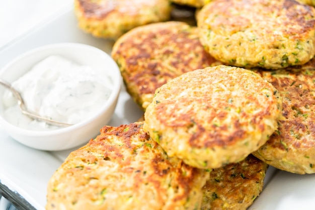 Torte di zucchine fritte fresche su un vassoio da portata.