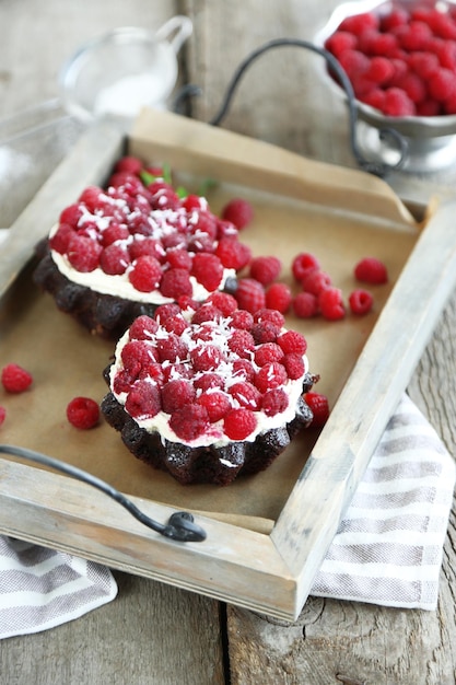 Torte dolci con lamponi su sfondo tavolo in legno