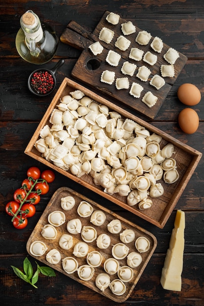 tortellini di ravioli italiani crudi con parmigiano fresco e basilico, pomodori su un vecchio tavolo di legno scuro