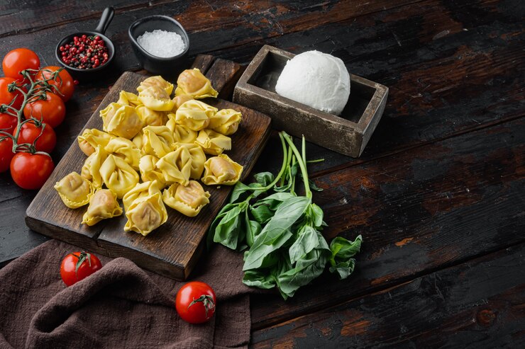 Foto tortellini fatti in casa con formaggio e basilico insieme, sul tagliere di legno, sul vecchio tavolo in legno scuro