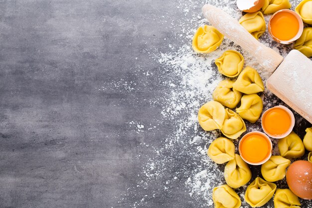 Tortellini italiani crudi fatti in casa e foglie di basilico.