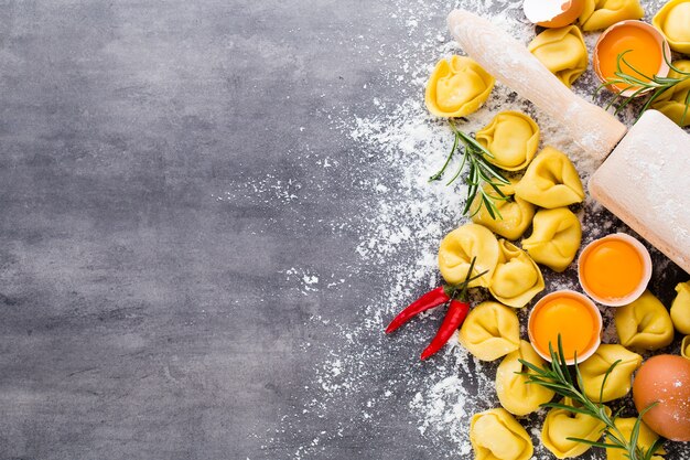 Tortellini italiani crudi fatti in casa e foglie di basilico.