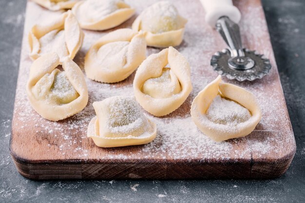 Tortellini o ravioli fatti in casa crudi freschi sul primo piano scuro del fondo