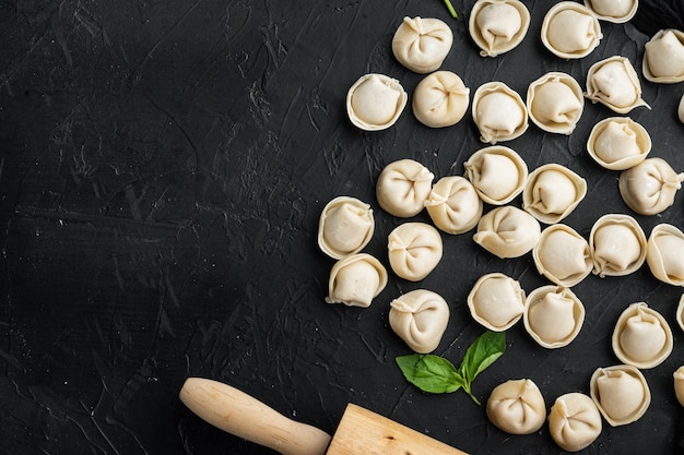 Tortellini set di ingredienti, su sfondo nero, vista dall'alto piatto laici,