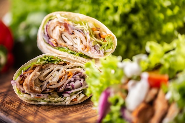 Tortilla avvolge con carne, verdure, maionese con insalata sul lato.