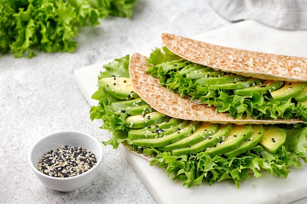 Tortilla di focaccia con avocado e lattuga Verde sano Panino facile da cucinare su sfondo grigio