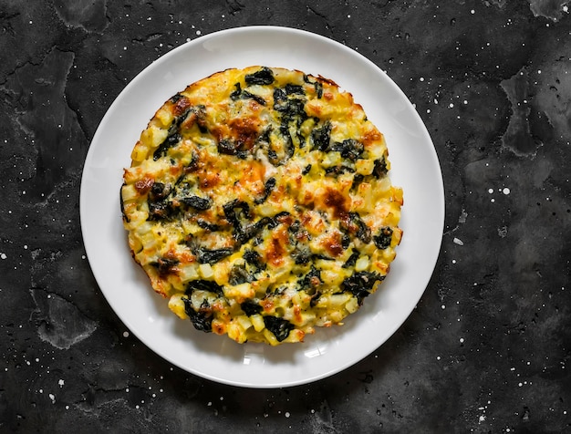 Tortilla di spinaci di patate deliziose tapas spuntino per la colazione su uno sfondo scuro vista dall'alto