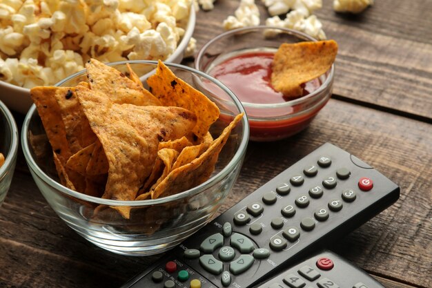 Tortilla e popcorn, telecomando della TV su un fondo di legno marrone. concetto di guardare film a casa. avvicinamento.