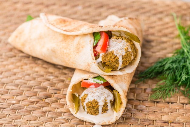 Tortilla Falafel shawarma wrap servito in un piatto isolato sul tavolo vista laterale del cibo arabo