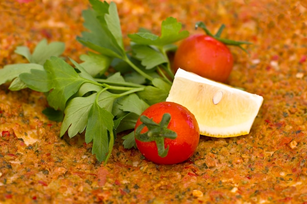 Tortilla turca pita con carne macinata e spezie, con pomodorini e foglie di prezzemolo.