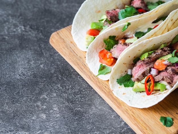 Tortillas con verdure e fette di bistecca di manzo. Avocado, pomodori, cipolle rosse e incontro con coriandolo e succo di lime nelle tortillas. Cibo messicano.