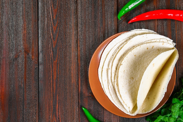 Tortillas di grano integrale su tavola di legno e verdure.